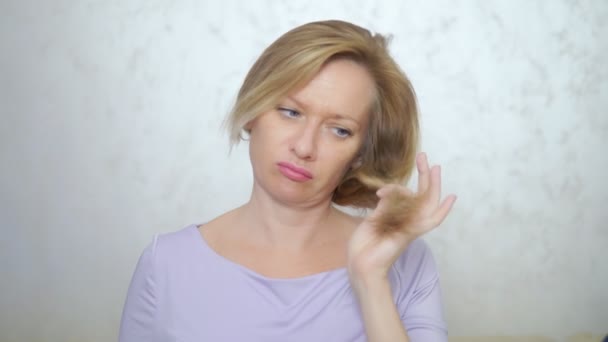 Concetto di capelli lunghi danneggiati. donna bionda taglia i capelli con le forbici . — Video Stock