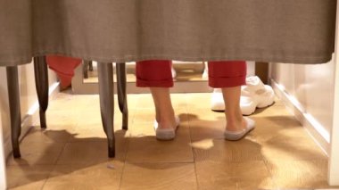 kadın bacakları bir giyim mağazasının montaj odasında perdelerin altından görülebilir.