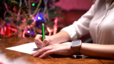 iş kadını dekore edilmiş bir Noel ağacının yanındaki masada oturur ve Noel Baba'ya bir Noel mektubu yazar.