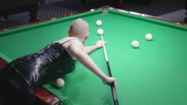 Stylish bald girl in a black leather corset plays billiards. — Stock Video