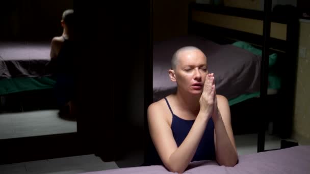 대머리 여자는 침실에서 침대에 무릎을 꿇고기도합니다. 복사 공간 — 비디오
