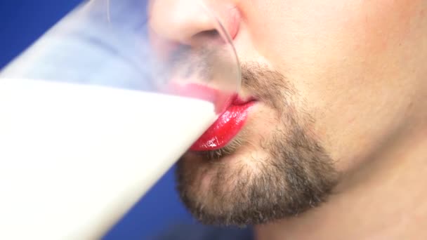 Close-up. um homem barbudo com lábios pintados bebe leite de um copo . — Vídeo de Stock