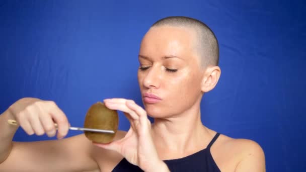 Attraktive glatzköpfige Frau rasiert eine Kiwi mit einem gefährlichen Rasiermesser. Konzept des Humors, Abenteuer fremder Menschen. — Stockvideo