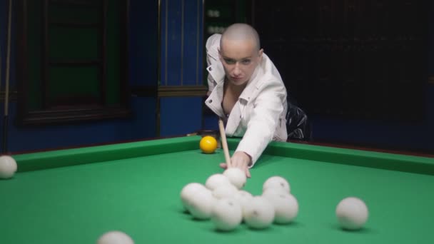 Stylisches glatzköpfiges Mädchen in weißer Lederjacke spielt Billard. — Stockvideo