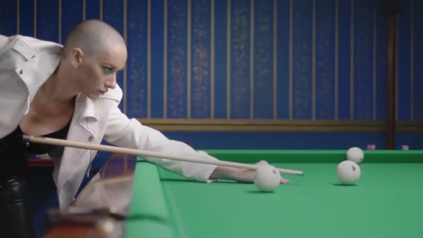 Stylish bald girl in a white leather jacket plays billiards. — Stock Video