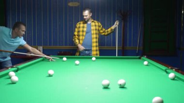 Bilardo kulübünde bilardo oynayan iki adam.