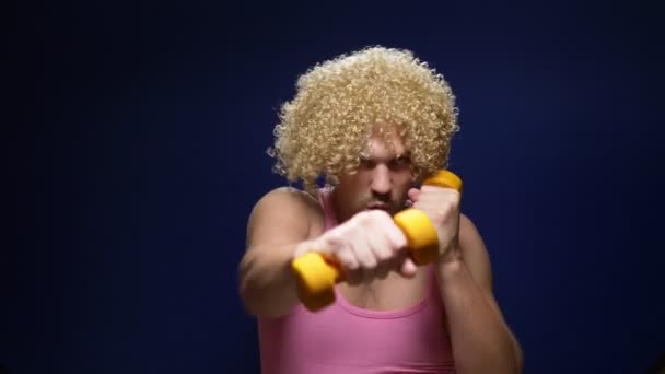 Gekke man atleet in een pruik met halters tegen een donkere achtergrond — Stockvideo