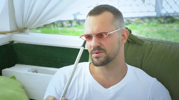 Hookah outdoors. handsome man smokes a hookah in the gazebo on a summer sunny day — Stock Photo, Image