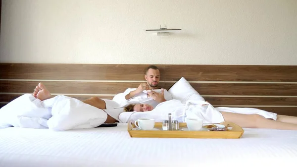 Junges Paar, das morgens zusammen im Bett liegt, frühstückt im Bett — Stockfoto