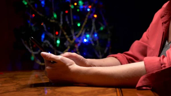 Feliz Ano Novo e Feliz Natal. close-up. mãos femininas SMS mensagem sms no smartphone — Fotografia de Stock