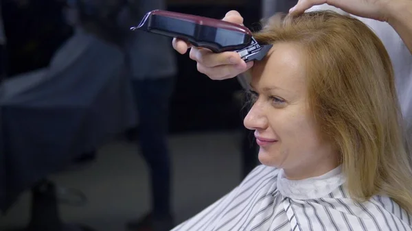 Kvinna rakning huvudet balt. en frisör rakar en kvinnas långt hår med en hårklippare. — Stockfoto