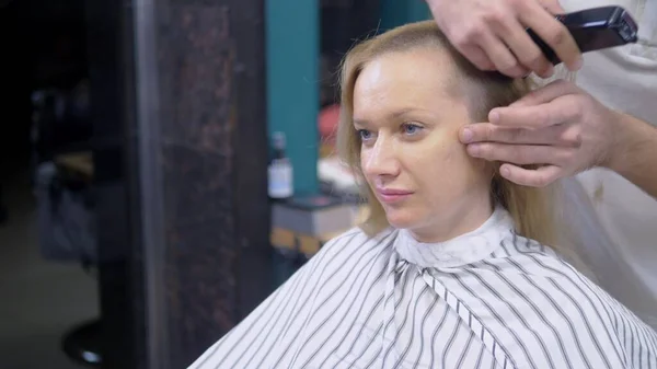 Vrouw scheren haar hoofd baldly. een kapper scheert een Womans lang haar met een haar Clipper. — Stockfoto