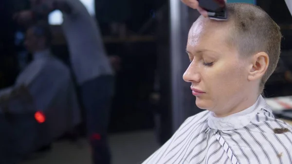 Conceito de perda de cabelo após a quimioterapia. o cabeleireiro rapa o resto do cabelo na cabeça de uma mulher careca que sobreviveu após a quimioterapia. esperança de sobrevivência . — Fotografia de Stock