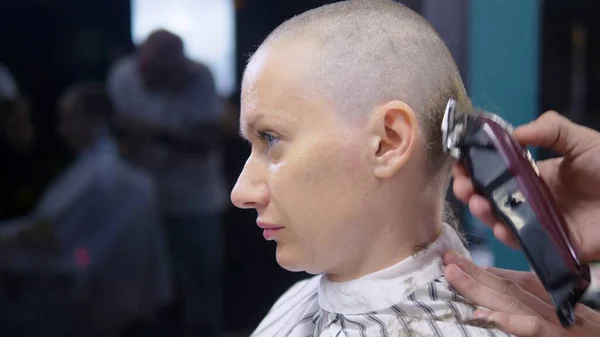 Conceito de perda de cabelo após a quimioterapia. o cabeleireiro rapa o resto do cabelo na cabeça de uma mulher careca que sobreviveu após a quimioterapia. esperança de sobrevivência . — Fotografia de Stock