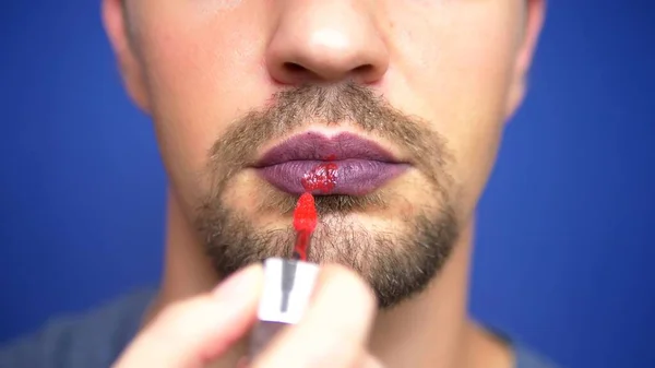 Close-up. a bearded man paints his lips. — Stock Photo, Image