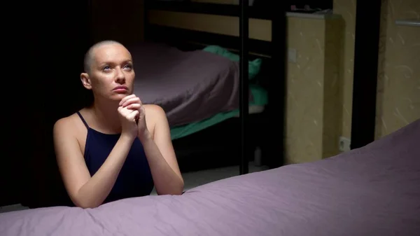 bald woman prays kneeling by the bed in the bedroom. copy space