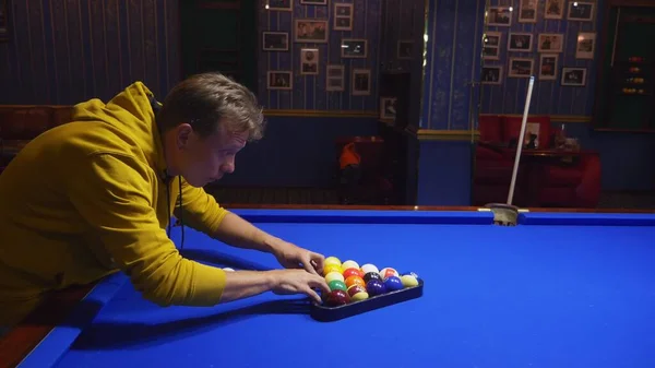 fashionable guy puts on a pool table A full set of billiards in a triangular frame on a green frieze. copy space