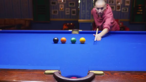 end goal achievement. a bald girl scores several balls in a row into a pocket. Beautiful bald woman plays american billiards.