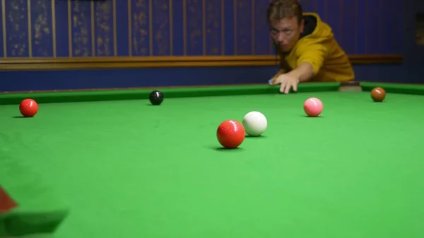 young male professional pool player playing snooker.