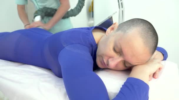 Łysa dziewczyna w fioletowym garniturze otrzymuje zabieg masażu lpg. — Wideo stockowe