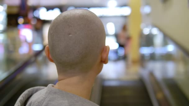 Bald woman rises up on the escalator. turns and looks at the camera. — Stock Video