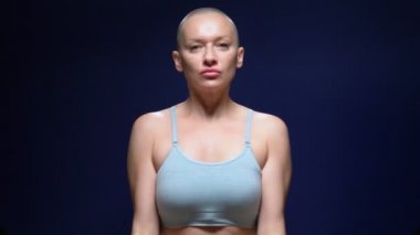 Sportif bluzlu kel kadın, arka planda kaslı kaslar gösteriyor.