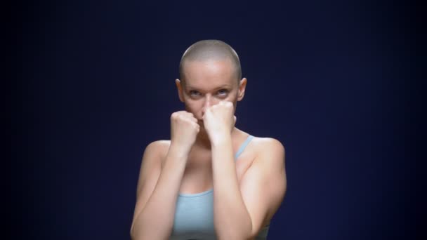 Careca mulher boxe para a câmera contra um fundo escuro — Vídeo de Stock