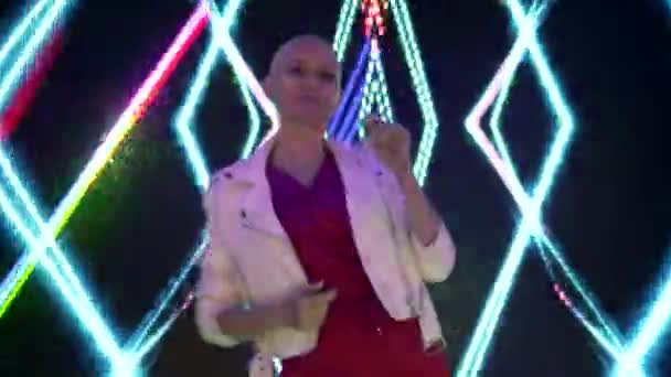 Klubbfest. Nattliv. skallig vacker flicka dansar i en klubb i färgglada strålar av en neon ljus disco — Stockvideo