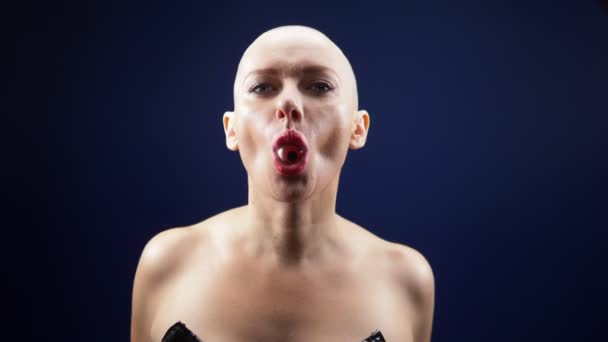 Extravagant skallig kvinna i svart läderkorsett äter godis i form av ett öga. Humor, halloween. mörk bakgrund — Stockvideo