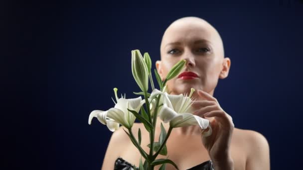 En vacker skallig kvinna i svart läderkorsett håller en vit lilja i sina händer. äventyr av främmande människor. — Stockvideo