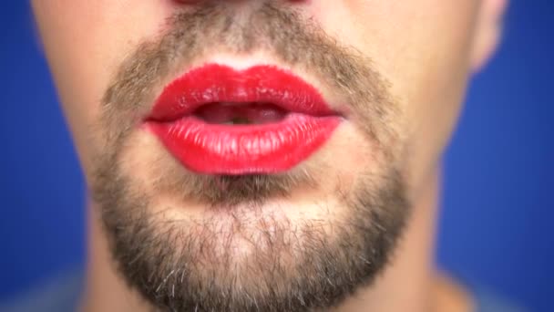 Close-up. Een man met een baard met beschilderde lippen glimlacht seksueel en geeft een kus. — Stockvideo