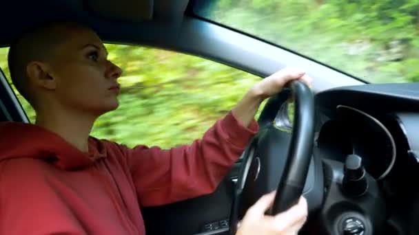 Una joven calva conduciendo un coche. viaje por carretera — Vídeo de stock