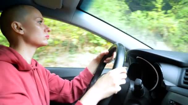 Łysa młoda kobieta prowadzi samochód. przejazd — Wideo stockowe