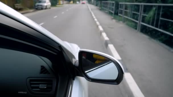 Retrovisor lateral de un coche mientras conduce por una carretera . — Vídeos de Stock