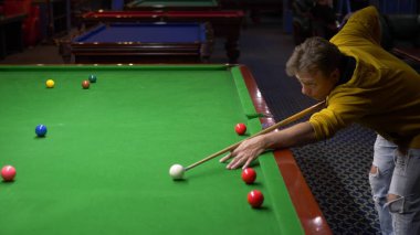 Genç adam, profesyonel bilardo oyuncusu Amerikan bilardosu oynuyor..