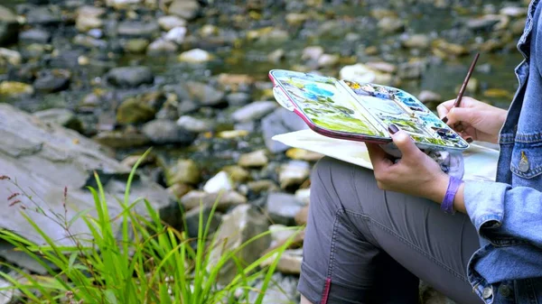接近中だ女性アーティスト。滝を背景に自然を大切にしていますパレットに絵を描き — ストック写真