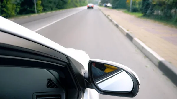 Retrovisor lateral de un coche mientras conduce por una carretera . — Foto de Stock