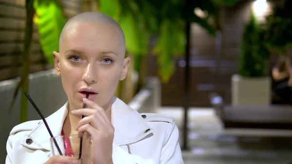 A bald young girl in a white leather jacket stands at an evening party on a beautiful terrace. copy space — Stock Photo, Image