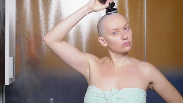 Una mujer calva se afeita la cabeza en el baño después de una ducha. Copiar espacio. aventuras de gente extraña — Foto de Stock