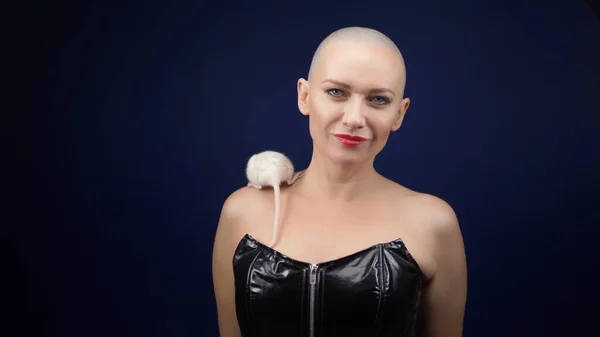 Beautiful bald woman in a black leather corset holds a white rat in her hands. adventures of strange people. animal, symbol of 2020 according to the Chinese horoscope. — Stock Photo, Image
