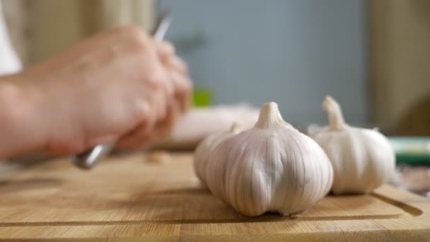 Detailní hlava česneku, mužské ruce oloupat česnek na dřevěné desce — Stock video