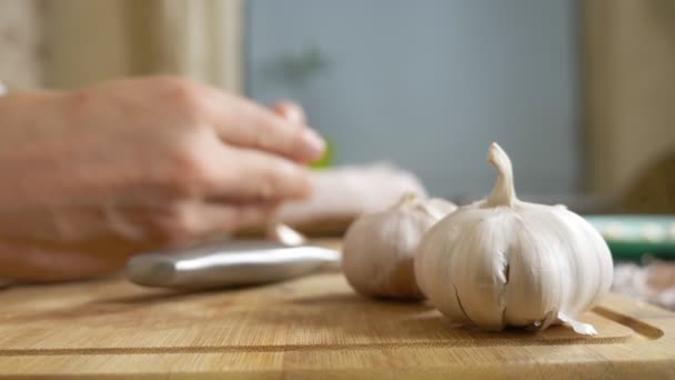 Closeup head of garlic, male hands peel the garlic on a wooden board — Stock Video