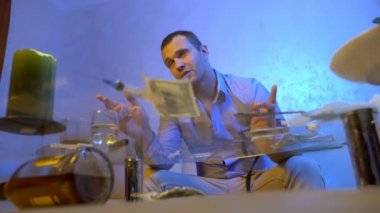 Genç bir adam, oturma odasındaki masanın yanında yerde yatarken alkol ve uyuşturucu almaktan halüsinasyonlar görür..