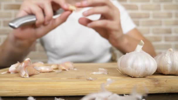 Testa di aglio primo piano, mani maschili sbucciare l'aglio su una tavola di legno — Video Stock