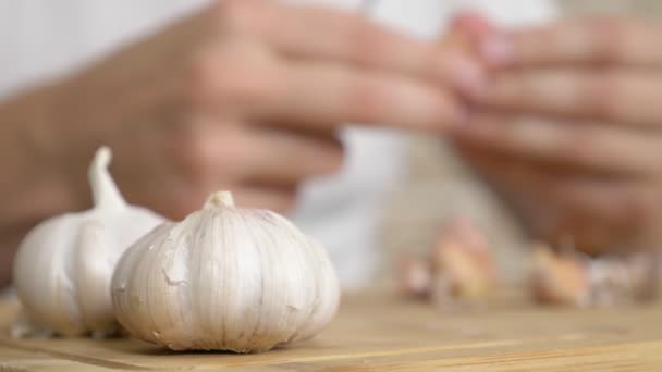 Closeup head of garlic, male hands peel the garlic on a wooden board — Stock Video