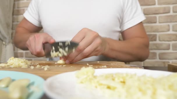 Mani maschili tagliano l'aglio su una tavola di legno. primo piano — Video Stock