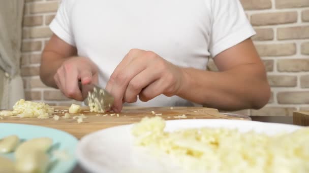 Las manos masculinas cortan el ajo en la tabla de madera. primer plano — Vídeos de Stock