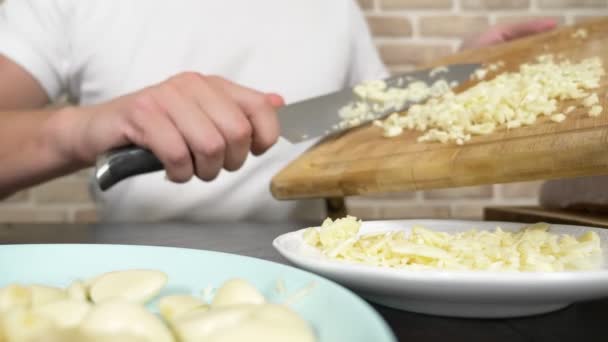 Męskie dłonie kroją czosnek na drewnianej desce. zbliżenie — Wideo stockowe