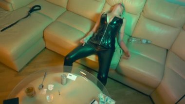 Deri korseli kel bir kadın kanepedeki oturma odasında aşırı dozdan kıvranıyor. Zehirli maddelere ve istismara bağımlılık kavramında, çoklu uyuşturucu kullanımı.