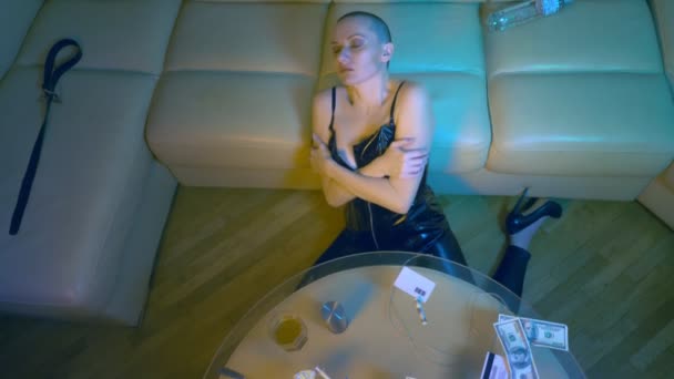 En skallig kvinna i läderkorsett skakar om i vardagsrummet på soffan. i begreppet beroende av giftiga ämnen och missbruk, blandmissbruk. — Stockvideo